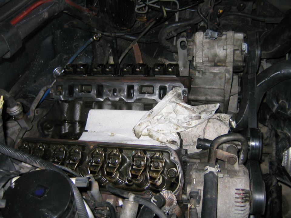 V8 engine with intake removed, rocker arms exposed and shop rags over the lifter valley