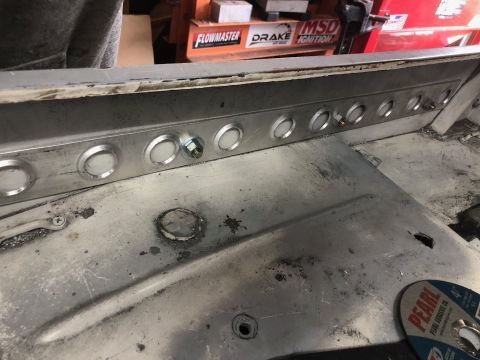 1992 Jeep Wrangler - A close-up view of a metal panel with multiple circular cutouts, some with fasteners, mounted inside a vehicle. The panel appears to be par…