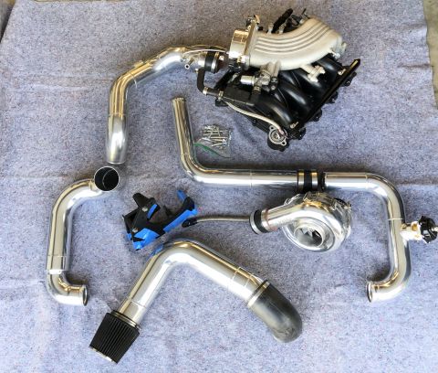 1998 Ford Crown Victoria - Aftermarket turbocharger and intake manifold kit components are displayed on a gray mat.