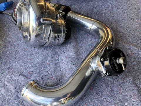 1998 Ford Crown Victoria - A polished supercharger assembly with associated piping is laid out on a grey, textured surface.