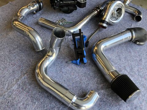 1998 Ford Crown Victoria - Polished aluminum intake piping and turbocharger components laid out on a gray surface.