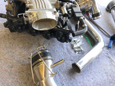 1998 Ford Crown Victoria - Engine intake manifold and associated polished aluminum piping parts are displayed on a textured surface.