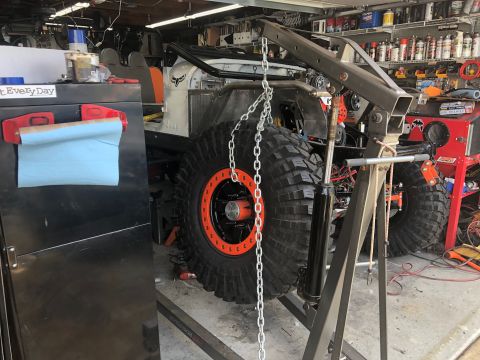1992 Jeep Wrangler - A heavily modified off-road vehicle is being worked on in a cluttered garage, with a chain hoist attached.