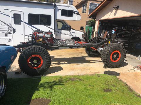 1992 Jeep Wrangler - The chassis of a Jeep is shown with its engine and massive off-road tires, suggesting a custom build or restoration project.