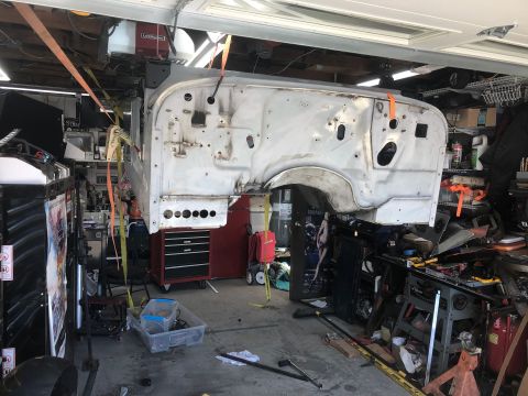 1992 Jeep Wrangler - Jeep body shell undergoing restoration, suspended in a garage with tools and parts around.