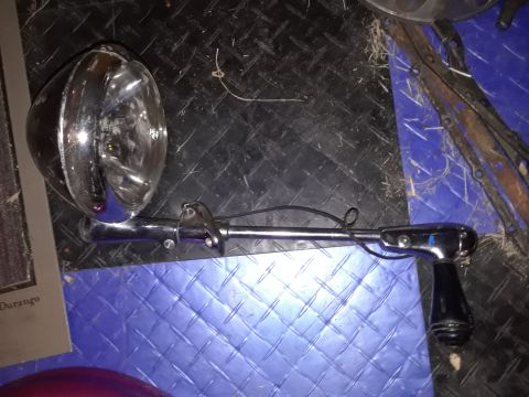 1994 Ford Bronco - Chrome spotlight with black handle and mounting bracket on a textured surface.