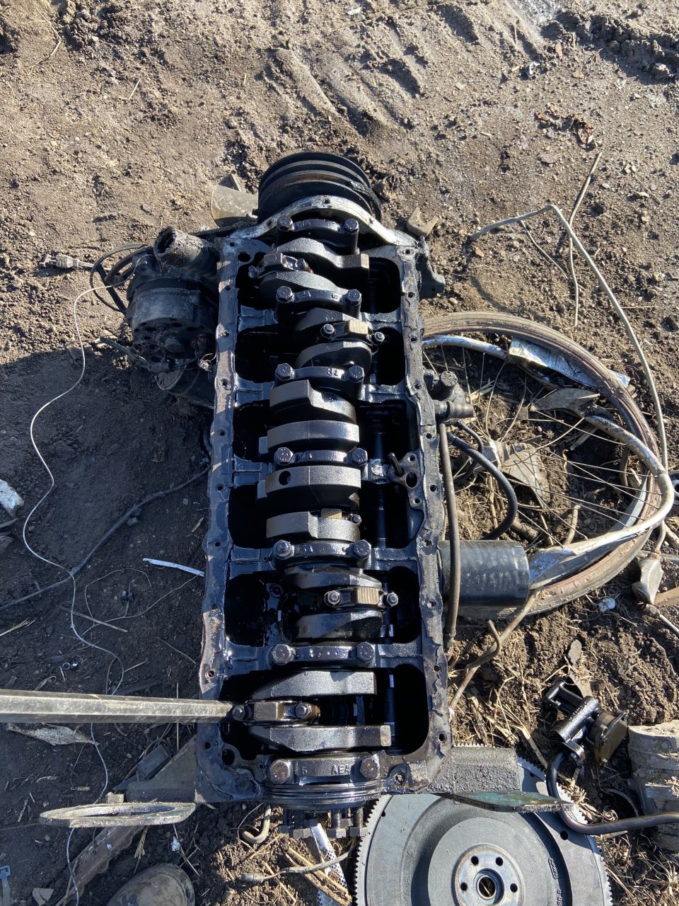 Engine block with crankshaft and some attached components, lying on the ground