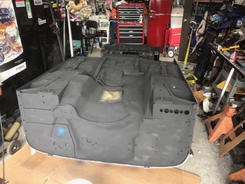 1992 Jeep Wrangler - The underside of a vehicle chassis is visible, undergoing restoration or repair in a cluttered garage environment.