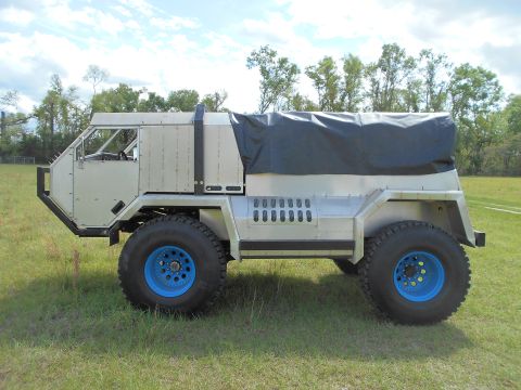 1992 Ford Bronco - This custom off-road truck features a unique design with bright blue wheels and a covered bed.