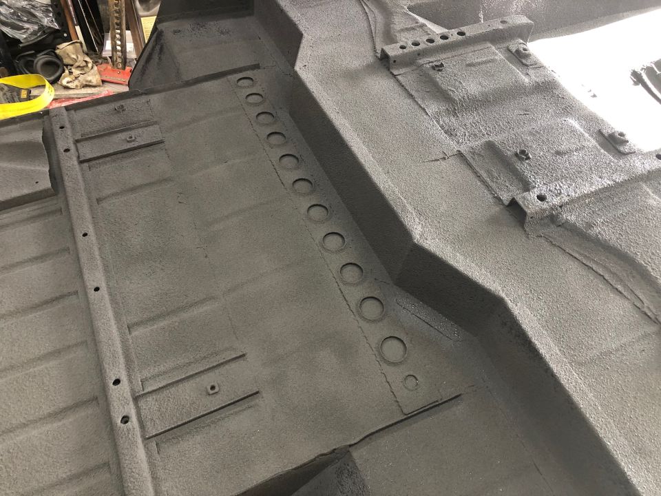 Gray vehicle undercarriage with visible floor pan, frame rails, and mounting points