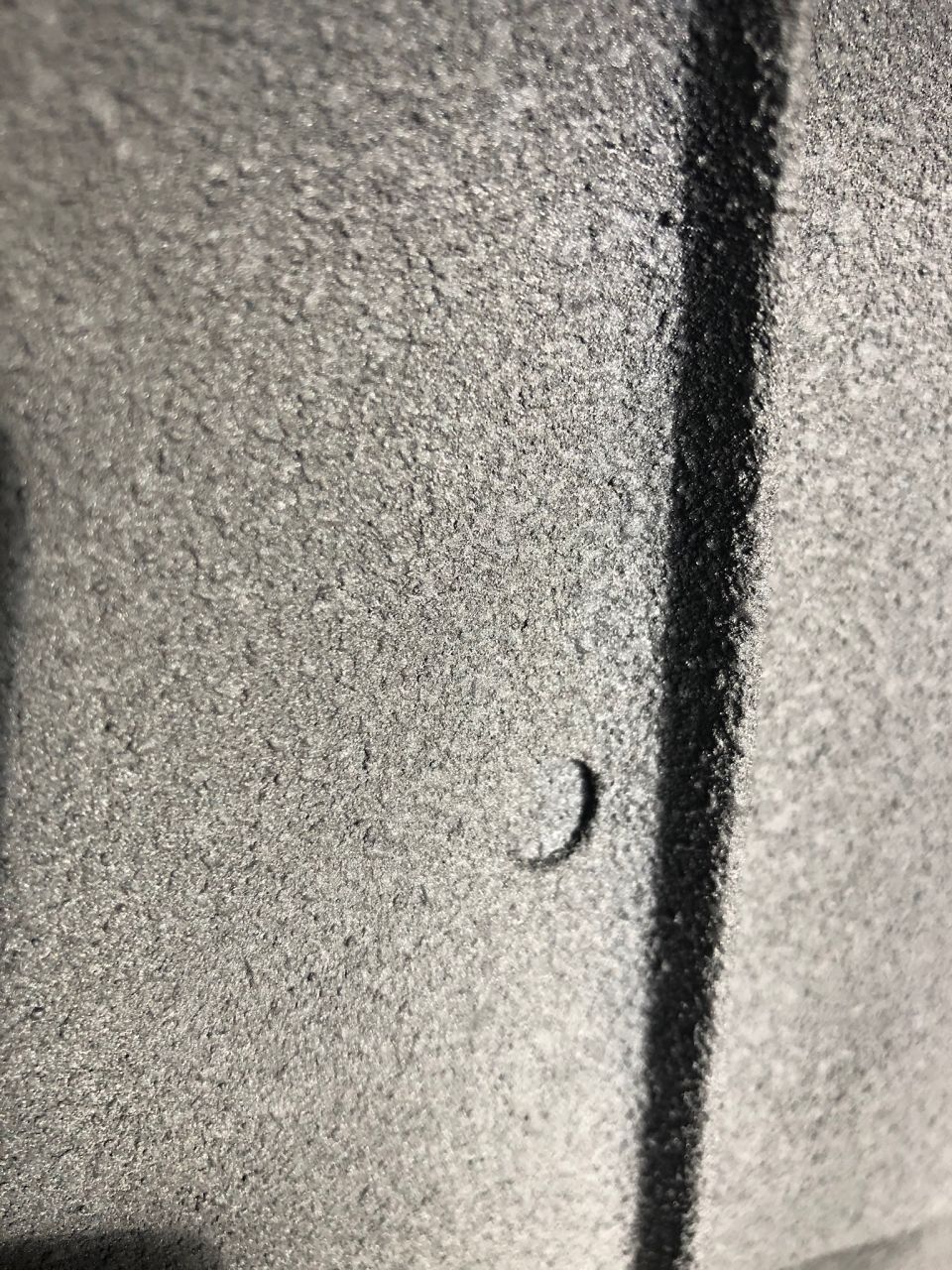 Close-up of a gray textured surface with a black line and a small crescent-shaped indentation. Supermotors.net logo visible