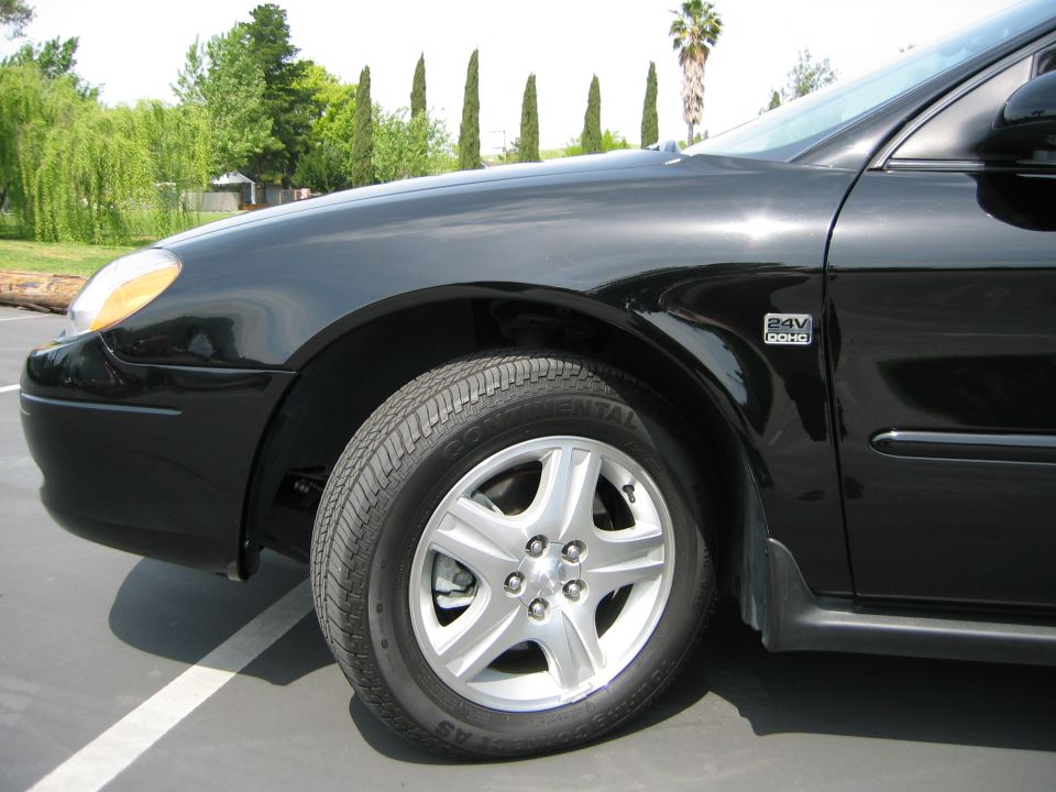 Front fender and wheel of a black 2002 Ford Taurus
