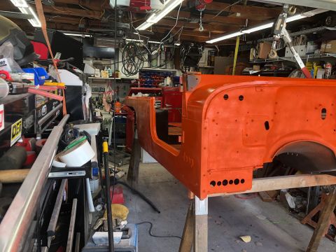 1992 Jeep Wrangler - The body of an orange Jeep Wrangler is supported by sawhorses in a cluttered garage, indicating a restoration project.