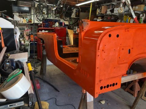 1992 Jeep Wrangler - Orange Jeep tub body undergoing restoration, supported by sawhorses in a workshop setting.
