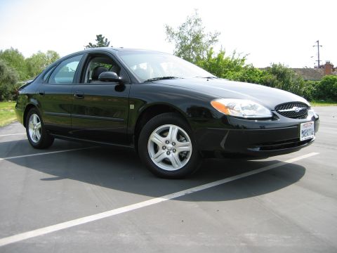 2002 Ford Taurus - A black 2002 Ford Taurus is parked in a lot, showing its front passenger side.