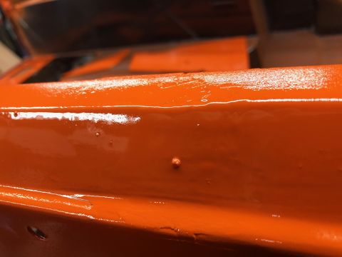 1992 Jeep Wrangler - A close-up view of a freshly painted orange surface, showing minor paint imperfections.
