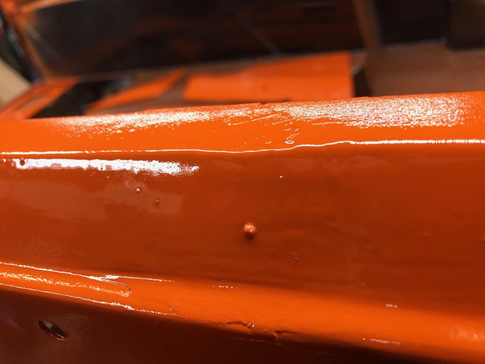 Close-up of orange painted metal with some imperfections and a watermark