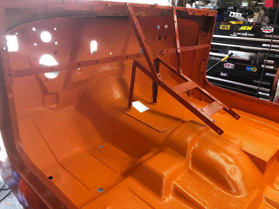 orange-painted interior of a vehicle body, likely a Jeep, with metal bracing installed