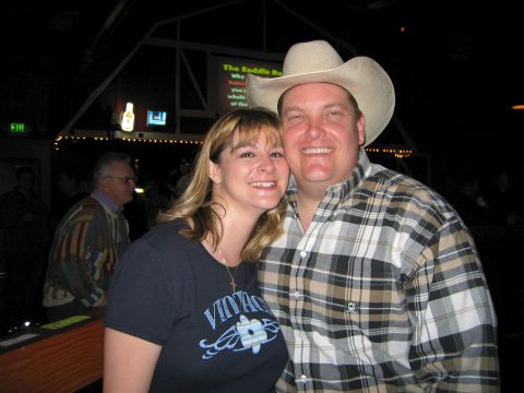 2002 Ford Taurus - A couple smiles for the camera inside a bar with a screen displaying text in the background.