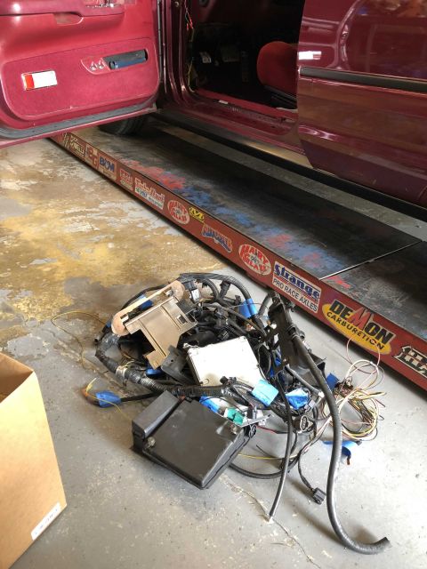 1992 Ford Crown Victoria - A tangled mess of vehicle wiring and electronic control units sits on the floor, partially obscuring a car's interior.