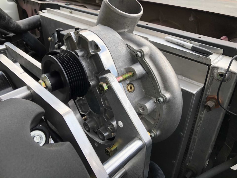 Close-up of a supercharger mounted near a radiator, with a black marker on top