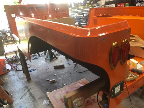 1992 Jeep Wrangler - The rear section of an orange Jeep is undergoing restoration in a garage setting.