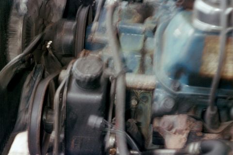 1979 Ford Bronco - Slightly blurred engine bay close-up of a blue-painted Ford V8, showing the power steering pump with its capped reservoir and V-belt pulley…