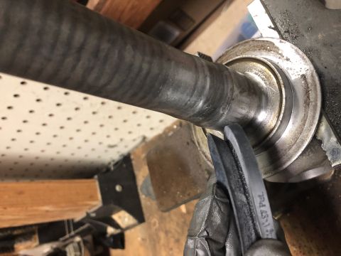 1980 Ford Bronco - A gloved hand uses a pry tool on a vehicle's driveshaft and bearing assembly.