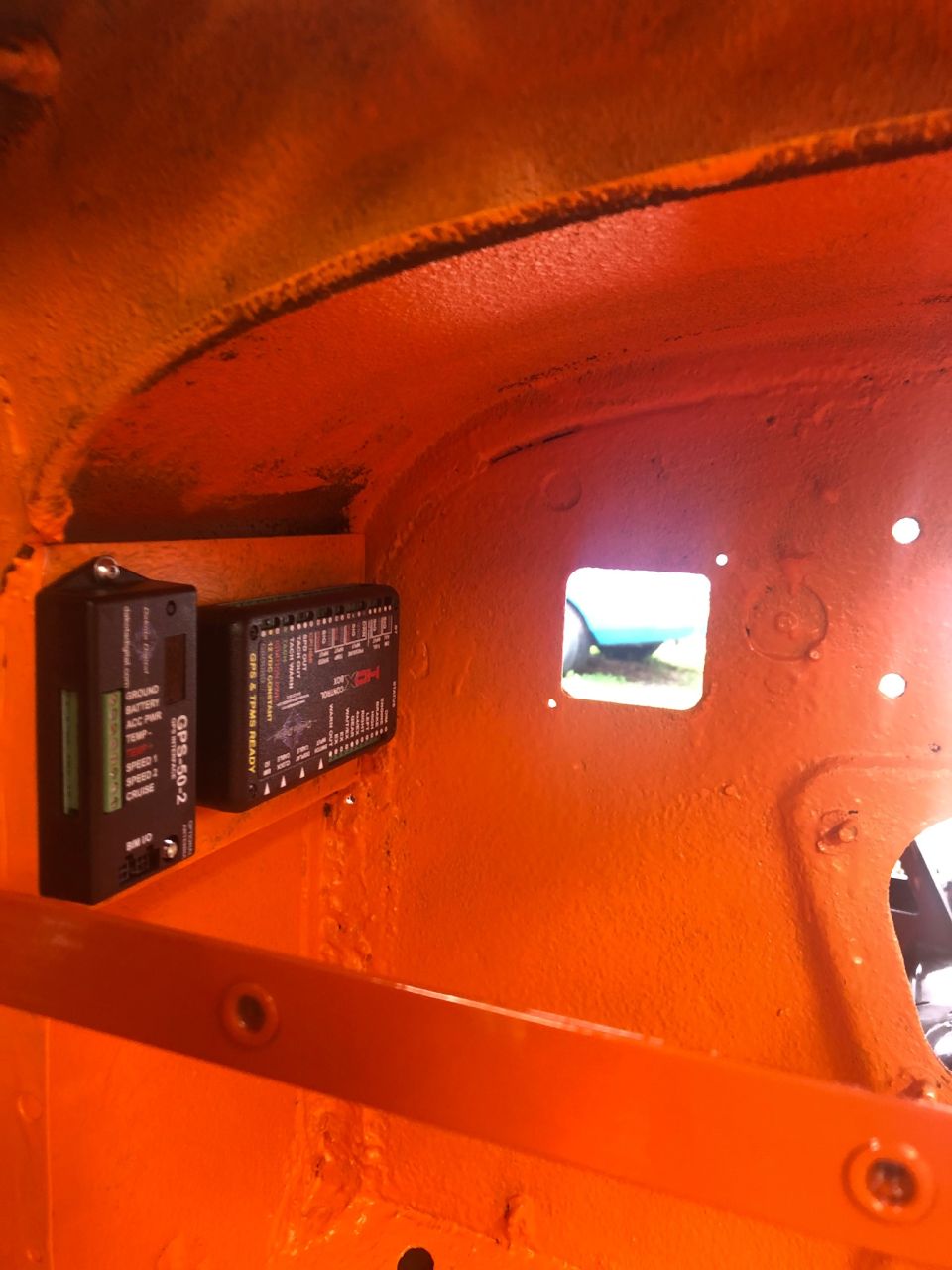 Interior of an orange vehicle showing two electronic modules mounted on the inner panel. One module is labeled GPS-50-2