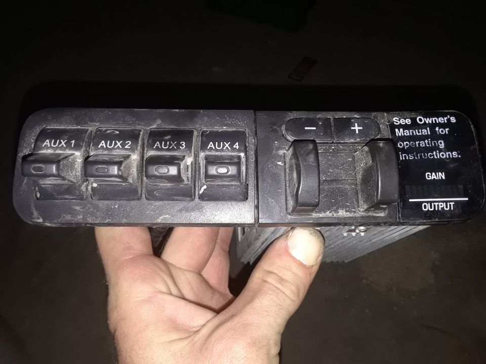Hand holding a trailer brake controller with four auxiliary switches, gain, and output controls