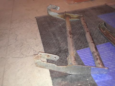 1994 Ford Bronco - These appear to be rusted bumper parts, possibly from a Ford Bronco, lying on a textured floor.