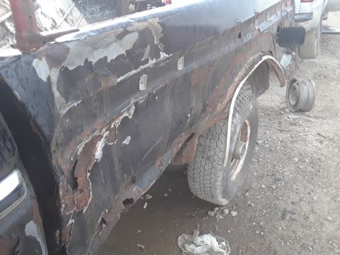 1994 Ford Bronco - This heavily rusted truck bed and rear fender shows significant deterioration and peeling paint.