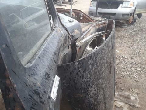 1994 Ford Bronco - A severely damaged truck sits in a junkyard next to another vehicle.