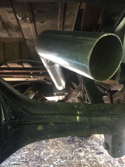 1979 Ford Bronco - Close-up view of the undercarriage of a vehicle, focusing on the exhaust system and rear axle components.
