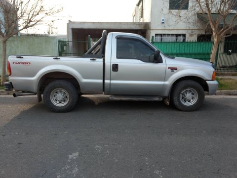 1992 Ford Bronco - A silver Ford F-250 pickup truck is parked on a residential street. The truck has a roll bar and turbo badging.