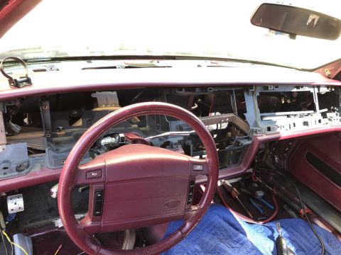 1992 Ford Crown Victoria - The dashboard of a car is disassembled, revealing wires and internal components, with tools laid out on the floor.