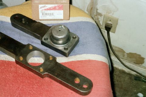 1979 Ford Bronco - Two metal steering components, likely for a vehicle, are laid out on a blanket next to a box.