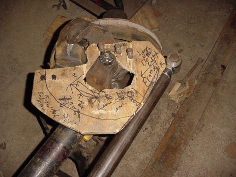 1992 Ford Bronco - A wooden jig with handwritten notes and diagrams is attached to a vehicle axle housing, likely for modification or measurement.