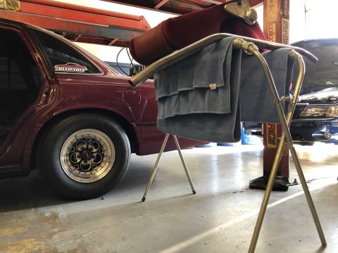 1992 Ford Crown Victoria - A maroon 1992 Ford Crown Victoria is parked in a garage, showing its racing tires and side profile.