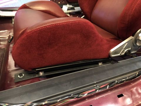 1992 Ford Crown Victoria - Close-up of a red velour and leather car seat, showing the seat base and mounting hardware.