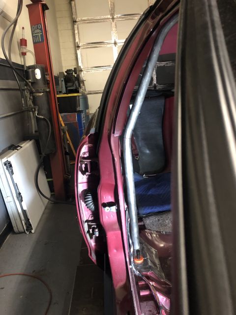 1992 Ford Crown Victoria - The interior door frame of a red car shows a silver roll cage, suggesting modifications for racing or performance.