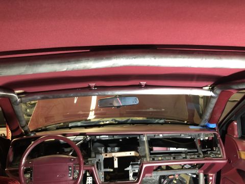1992 Ford Crown Victoria - The interior of a 1992 Ford Crown Victoria shows a roll cage installed over the burgundy dashboard and seats.