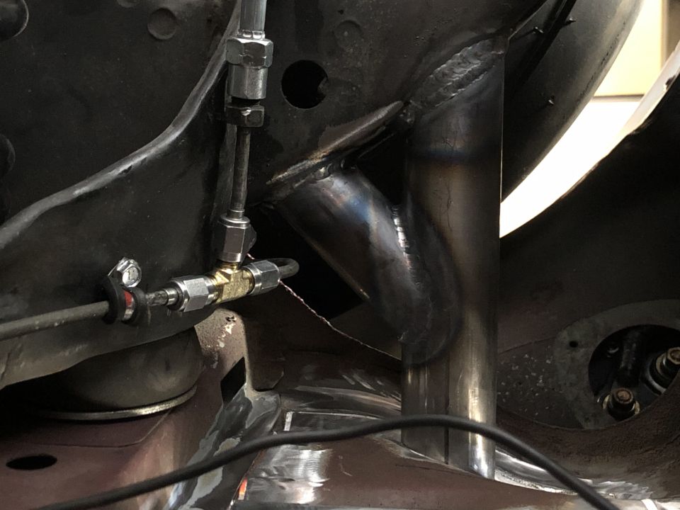 Close-up of welded metal frame with brake lines and cables attached