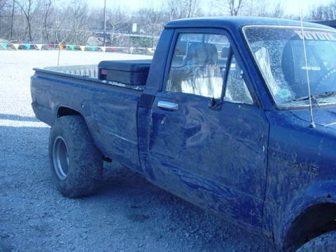 1992 Ford Bronco - A blue pickup truck is seen from the side, covered in dirt, with a black toolbox in the bed.