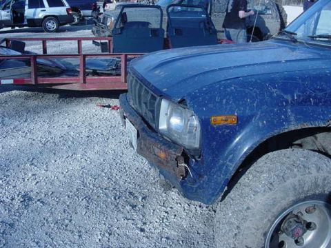 1992 Ford Bronco - Front view of a blue pickup truck, with a trailer in the background.