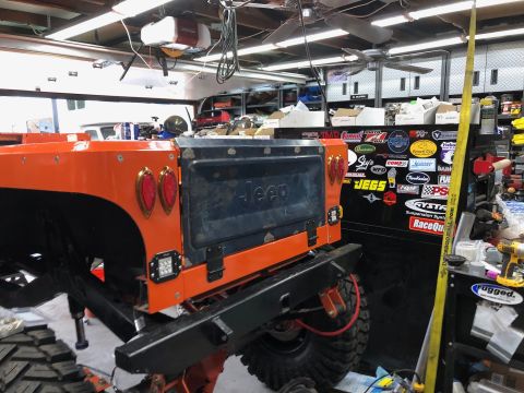1992 Jeep Wrangler - Rear view of an orange 1992 Jeep Wrangler undergoing work in a garage.