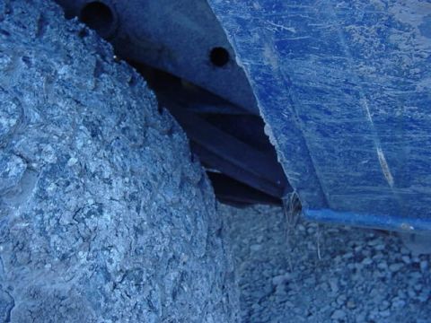 1992 Ford Bronco - The underside of a vehicle, showing a tire and blue body panel, with gravel on the ground.