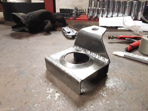 1985 Toyota Hilux - A fabricated metal bracket sits on a workbench next to various tools and a glove.