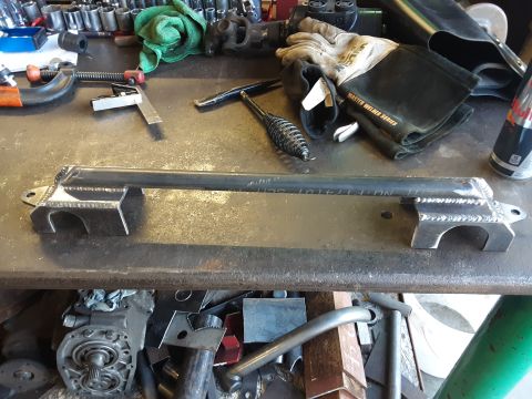 1985 Toyota Hilux - Custom metal part with visible welding and bracketry on a cluttered workbench.