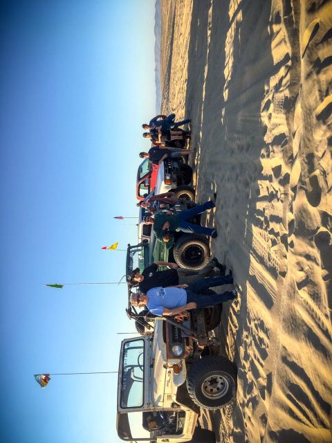 1996 Dodge 1500 - Several off-road vehicles and people gathered on sand dunes under a clear blue sky.